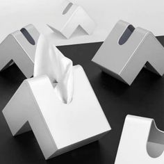 three tissue dispensers on a black table with white napkins in them