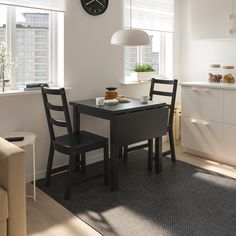 a kitchen table with two chairs and a clock on the wall in front of it