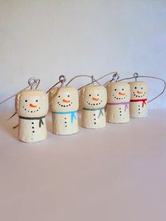 five snowmen are lined up in the shape of small wooden pegs, one is wearing a bow tie