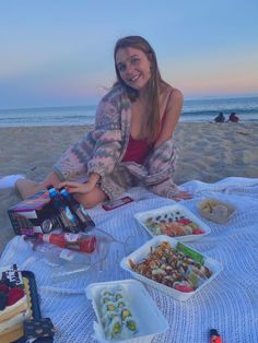 a woman sitting on the beach with some food