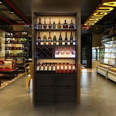 an empty restaurant with many bottles of wine on the shelves and food in the back