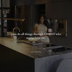 a woman standing in a kitchen holding a coffee cup and looking at the counter top