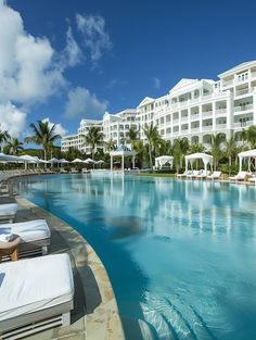 an outdoor swimming pool with lounge chairs and umbrellas