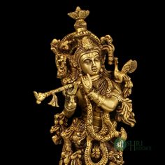 a golden statue with an ornate design on it's face and arms, holding a flute