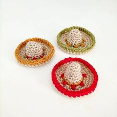 three small crocheted baskets with hats on them