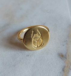 A beautiful handmade signet ring made of yellow gold plated silver 925o.  Round shaped signet ring with an engraved Scarab/Beetle on its surface. Totally handmade by a Greek designer in mat finish with a dainty design. Easy to wear as a statement ring. This ring comes in all sizes, so you can order it at your size and we will have your ring customised for you. Adjustable Yellow Gold Brass Signet Ring, Handmade 14k Gold Signet Ring As Gift, Oval Brass Signet Ring As Gift, Engraved Gold Plated Signet Ring As Gift, Engraved Gold Plated Signet Ring For Gift, Handmade Brass Yellow Gold Signet Ring, Handmade Yellow Gold Brass Signet Ring, Gold Oval Engraved Brass Ring, Gold Etched Sterling Silver Rings