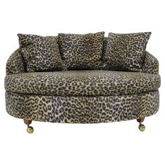 a leopard print couch with two pillows on it's back and one arm in the middle