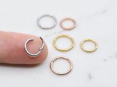 four different types of rings sitting on top of a white table next to a finger