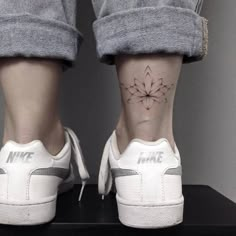 a woman's foot with a flower tattoo on her left ankle and the word nike written in white ink