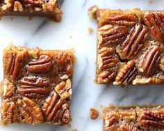 four pieces of pecan bars sitting on top of a marble counter