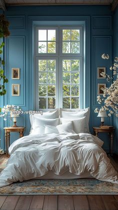 a bedroom with blue walls and white linens on the bed in front of a large window