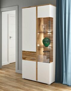 a white and wood cabinet with glass doors in a room next to a blue curtain