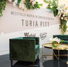 two green velvet chairs sitting in front of a wall with flowers on it and the words westfield women in conversation with turia pitt