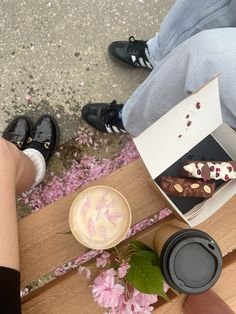 two people sitting at a table with some food and drinks in front of them on the ground