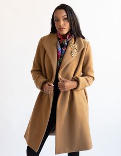 Discover the epitome of American-made elegance with this classic camel colored wool coat. This timeless knee-length coat is not only stylish but also provides exceptional warmth. Crafted with meticulous attention to detail, it features a fully lined body and sleeves, in a contrasting stripe lining.Designed for both style and functionality, this camel coat boasts a deep collar, deep on-seam side pockets, and adjustable cuffs, ensuring a perfect fit for arms of all lengths. For a secure closure, w Camel Lapel Collar Outerwear For Work, Camel Long Coat For Workwear, Camel Long Coat For Work, Beige Wool Shawl Collar Outerwear, Elegant Brown Outerwear With Shawl Collar, Camel Long Wool Coat For Workwear, Long Camel Wool Coat For Work, Chic Camel Wool Coat For Work, Camel Wool Outerwear With Lapel Collar