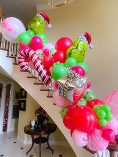 a bunch of balloons that are on a stair case in a house with a christmas theme