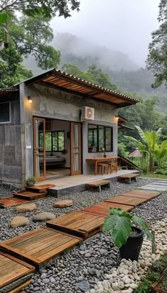 a small house in the middle of some rocks and trees with wooden steps leading up to it