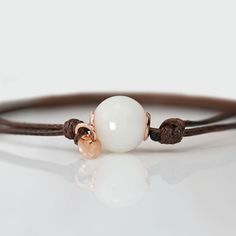 Beautiful handmade item! Here, on Etsy made as simulation only-just resin and white color.  Breastmilk pearl beaded bracelet with 1mm brown waxed cord.  Our  Simple Pearl Beads Bracelet is a pure and simple celebration of the natural beauty of motherhood. Sterling silver core in the central bead (rose or yellow gold options available). Add pearl powder for lustrous effect.  For all our breast milk bracelet collection, please visit: https://www.etsy.com/ca/shop/KeepsakeMom?ref=seller-platform-mcnav&section_id=27169694 For all breastmilk jewelry, please visit:  https://www.etsy.com/ca/shop/KeepsakeMom?ref=seller-platform-mcnav BREASTMILK JEWELRY NOTICE: For jewelry made with your own breast milk, please visit www.KeepsakeMom.com ETSY PROHIBITS THE SALE OF JEWELRY MADE WITH BREAST MILK; We se Handmade White Jewelry With Waxed Cord, White Waxed Cord Bracelet Perfect For Gifting, White Waxed Cord Bracelet As A Gift, White Waxed Cord Bracelets For Gifts, Everyday White Waxed Cord Bracelets, Breastmilk Jewelry, Silver Core, Simple Pearl, Pearl Powder