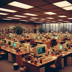 an office filled with computers and desks in front of large windows at night time