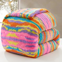 three multicolored towels stacked on top of each other in front of a window