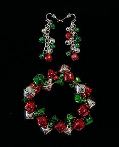 a pair of christmas jewelry is shown on a black background with red, green and silver beads