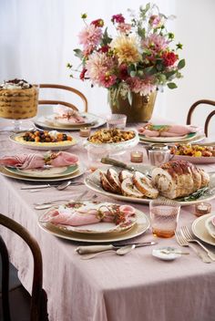 the table is set with many different types of food on plates and dishes, along with flowers