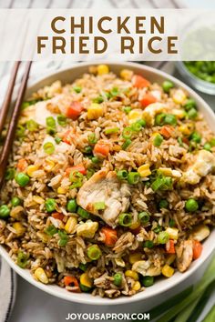 chicken fried rice in a white bowl with chopsticks and green onions on the side