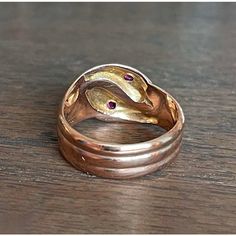 In the quiet, storied streets of Birmingham, 1918—a city teeming with industrious spirit and the echoes of a bygone era—a master goldsmith crafted this splendid creation. With its serpentine elegance, this ring features two serpents entwined in a dance of eternal allure. Each snake, rendered in lustrous 9 karat gold, showcases the hallmark of an era: the anchor for Birmingham and the letter 'T' denoting the year 1918, alongside the revered maker’s mark ‘H.W. Ld’. These symbols of authenticity promise not just a piece of jewelry, but a journey through time.  Adorning each serpent's head is a resplendent fuchsia-colored round faceted ruby measuring 2.6 mm across. These radiant gemstones capture the essence of a captivating twilight and reflect a world where opulence meets the extraordinary. Antique Hand Forged Rings For Formal Occasion, Vintage Hand Forged Yellow Gold Rings, Antique Hallmarked Snake Ring, Elegant Hallmarked Snake Ring, Antique Gold Snake Ring For Formal Occasions, Heirloom Style Snake Ring For Anniversary, Heirloom Snake Ring For Anniversary, Antique 14k Gold Snake Ring Gift, Antique 14k Gold Snake Ring For Anniversary