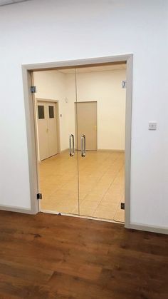 an empty room with wooden floors and mirrors on the wall, looking into another room