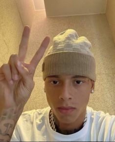 a young man making the peace sign with his hand and wearing a beanie hat