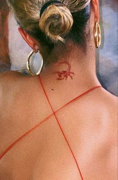 the back of a woman's neck with a crab tattoo on her left side