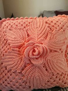 a pink crocheted pillow with a flower on it