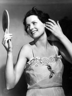 an old photo of a woman brushing her hair with a mirror in front of her