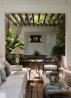 a living room filled with furniture and lots of greenery