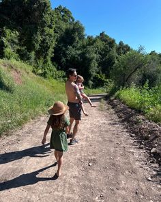 a man and two children walking down a dirt road