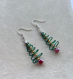 two green and red earrings sitting on top of a white towel