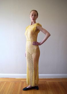 A vintage 1930s yellow lace gown with a small collar, ruffled flutter sleeves, and a low back. The lace fabric feels like cotton. There are no fasteners, but the fabric has give to fit over bust/shoulders. Size: xxs to small Bust: 28-34" Waist: 26-32" (will drape fine on slightly smaller, and 32" waist will need to fit over bust/shoulders because there are no fasteners at waist) Hip: 30-38" Length: 59-60" (will drape slightly shorter when dress is worn) Condition: Very good. Darkening in underarms and slight darkening at hem, but because of location, these flaws wouldn't be noticeable when dress is worn. A few tiny breaks in lace that look like part of pattern. Dress has been hand washed and presents as excellent. Fitted Floor-length Lace Dress With Scalloped Lace, Fitted Maxi Length Lace Dress With Scalloped Lace, Fitted Maxi Lace Dress With Ruffles, Fitted Maxi Length Lace Dress With Ruffles, Yellow Maxi Dress With Ruffles For Wedding, Yellow Wedding Maxi Dress With Ruffles, Yellow Lace Maxi Dress For Party, Yellow Fitted Dress With Lace Trim, Fitted Yellow Lace Dress