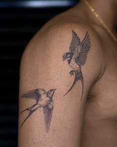 two birds flying next to each other on the back of a man's arm