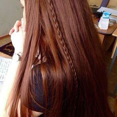 a woman with long red hair sitting in front of a desk and looking off to the side