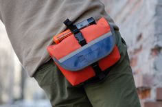 a man is holding his waist bag in one hand and looking down at the ground