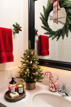 Add holiday cheer to your bathroom with these easy Christmas decor ideas! A festive red towel on the rack pairs perfectly with a wreath on the mirror, while a candle with a pine scent and holiday-themed soaps sit on the countertop. A mini Christmas tree in the corner, with tiny lights and ornaments, brings the seasonal spirit to the space. Sprinkle a bit of faux snow around the tree for a winter touch that’s both simple and festive. Red Christmas Bathroom Decor, Minimalist Christmas Bathroom Decor, Back Of Toilet Christmas Decor, Kids Bathroom Christmas Decor, Christmas Decor Ideas Maximalist, Christmas Ideas For Bathroom, Bathroom Decor Christmas Ideas, Bathroom Decorated For Christmas, Christmas Decor In Bathroom