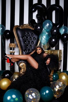 a woman is sitting in a chair surrounded by balloons and streamers as she poses for the camera