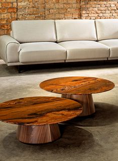 two wooden tables sitting in front of a white couch on top of a cement floor