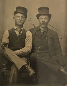 an old black and white photo of two men in hats sitting next to each other