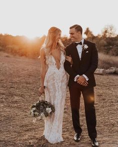 a bride and groom standing in the desert at sunset