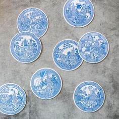 six blue and white plates sitting on top of a cement floor next to each other