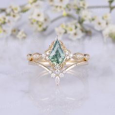 an engagement ring with a pear shaped green stone surrounded by white flowers