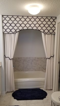 a bath tub sitting under a window next to a rug