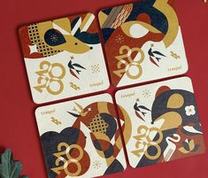 four coasters with designs on them sitting next to a potted plant and red wall