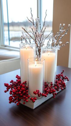 three candles are sitting on a tray with red berries